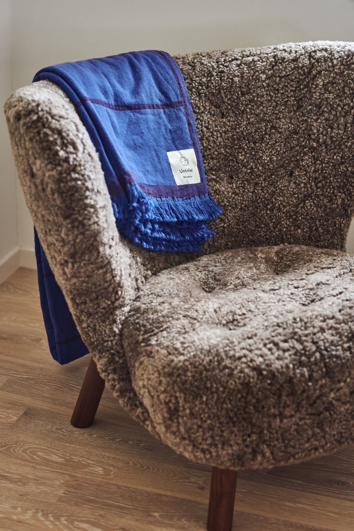 Here you see the Little Petra lounge chair in a fluffy sheepskin variant with the blue Untitled throw drapped over the top, both from &tradition. 