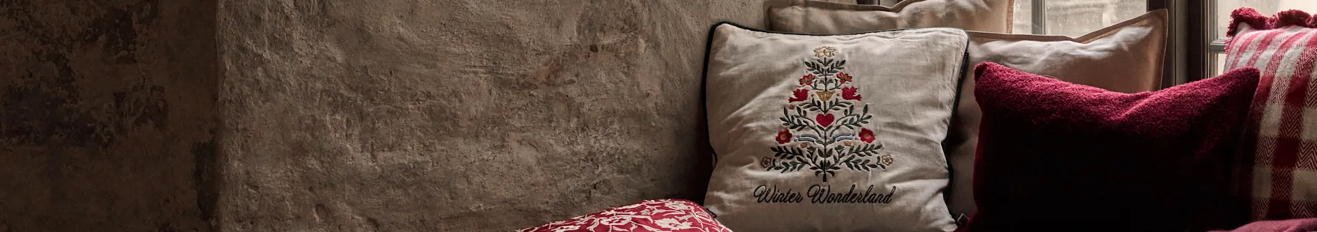 Pillows including an embroidered Christmas tree design with Winter Wonderland text, a dark red pillow, and a red and white checkered pillow.