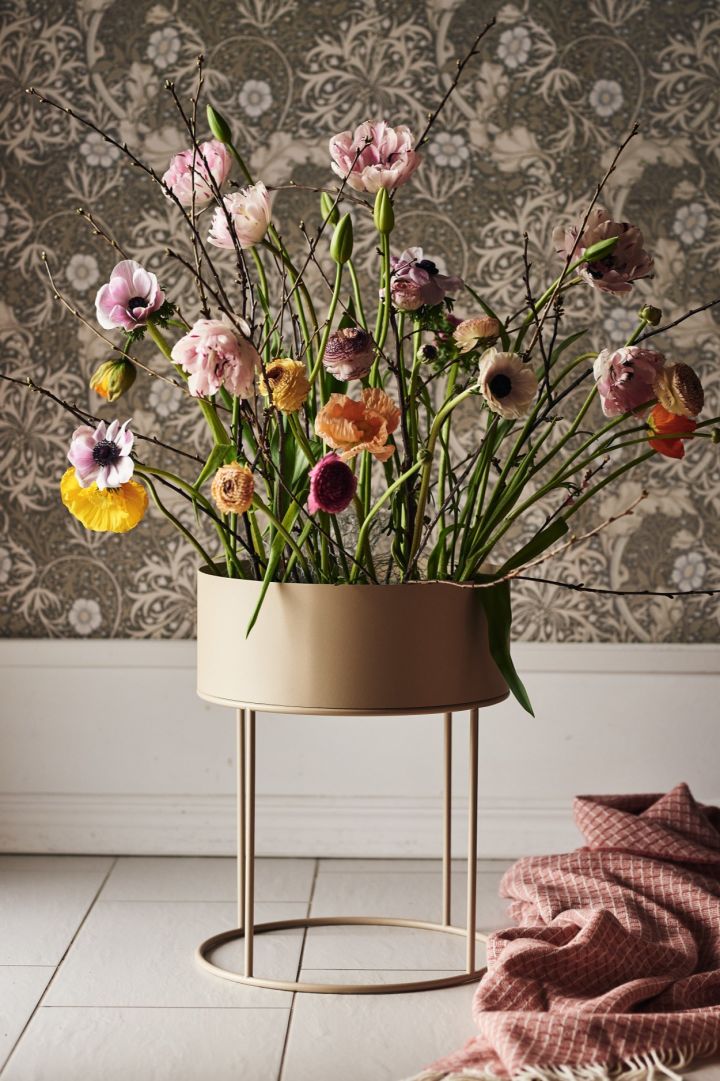 A large arrangement of fresh flowers in a free standing round plant box from Ferm Living. 