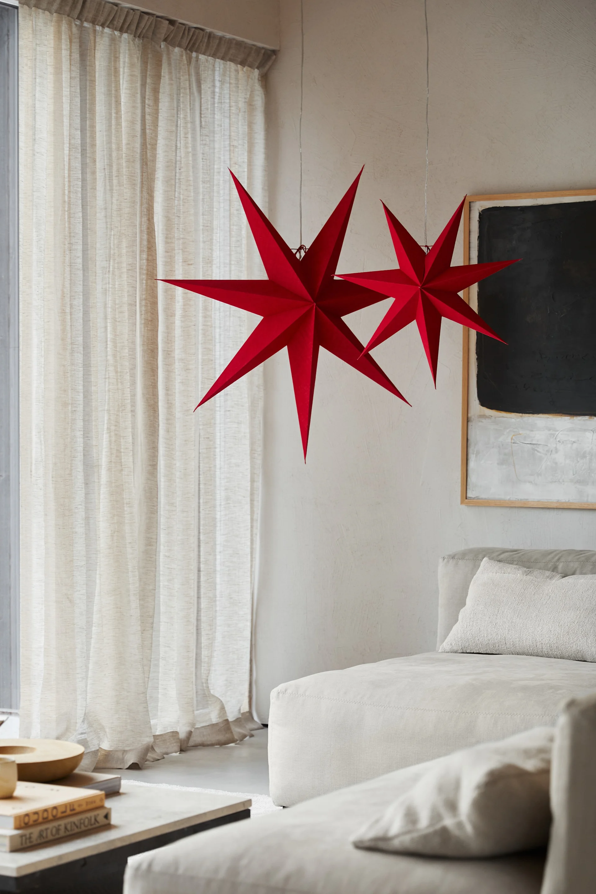 Two paper star lanterns in red from Watt & Veke in red hanging together in a living room. 