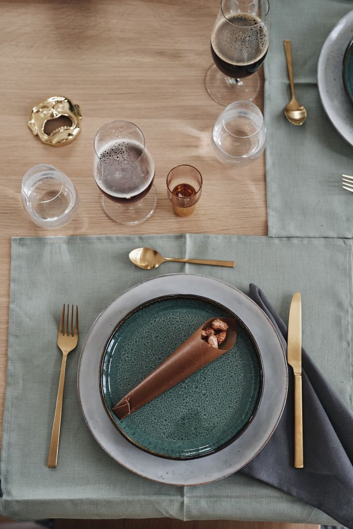 A green table setting on a green tea towel invites you to a cozy Christmas dinner.