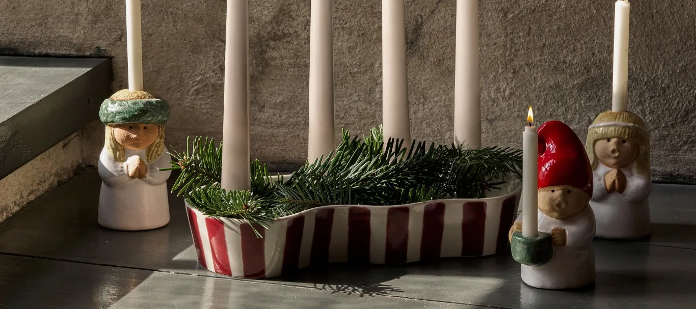 This year's Christmas decorations 2026 are joyful and nostalgic. A red striped candle holder is surrounded by small carol singer candle holders.