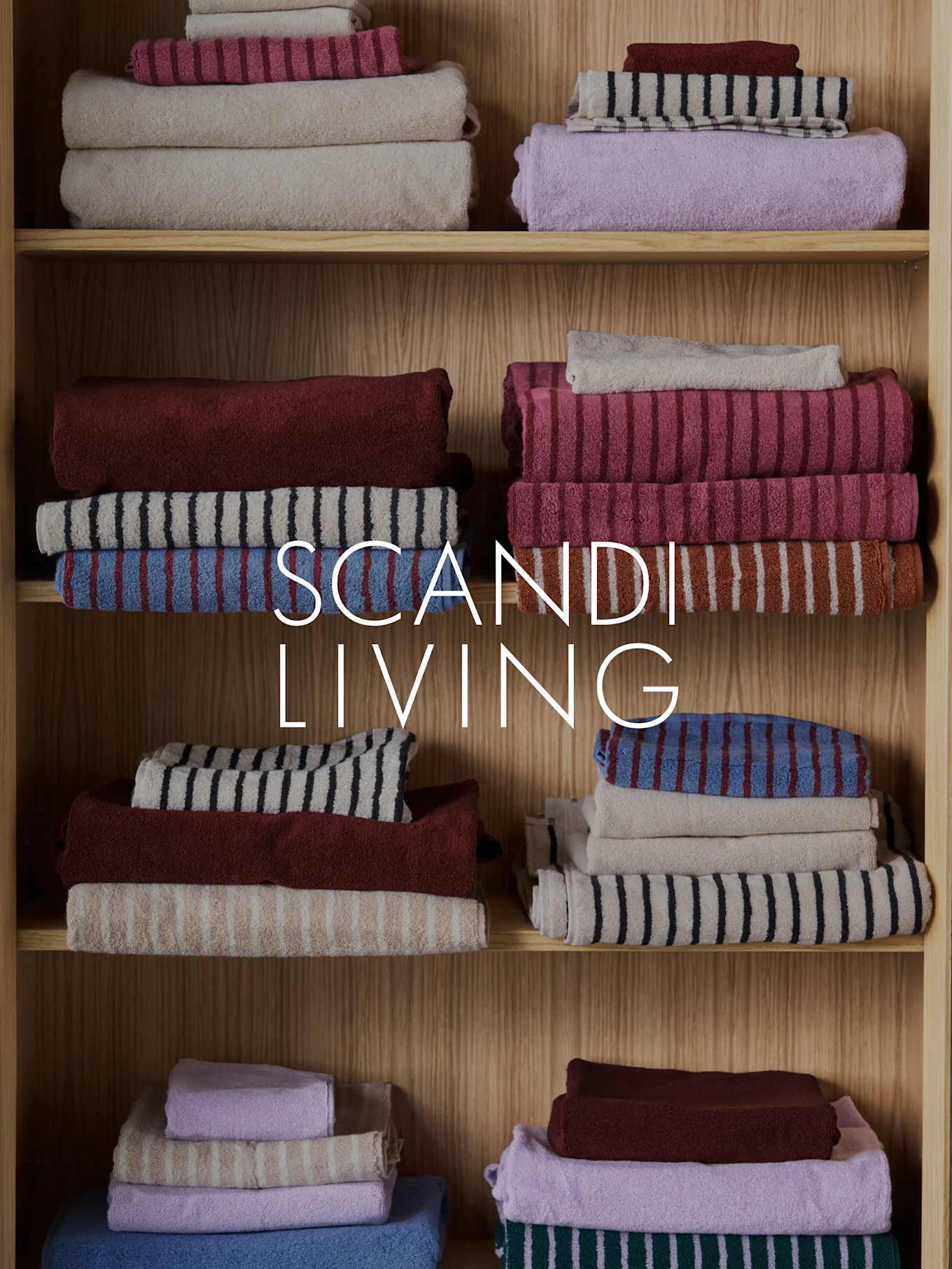 SCANDI LIVING text over stacked, folded towels in various colors and patterns on wooden shelves.