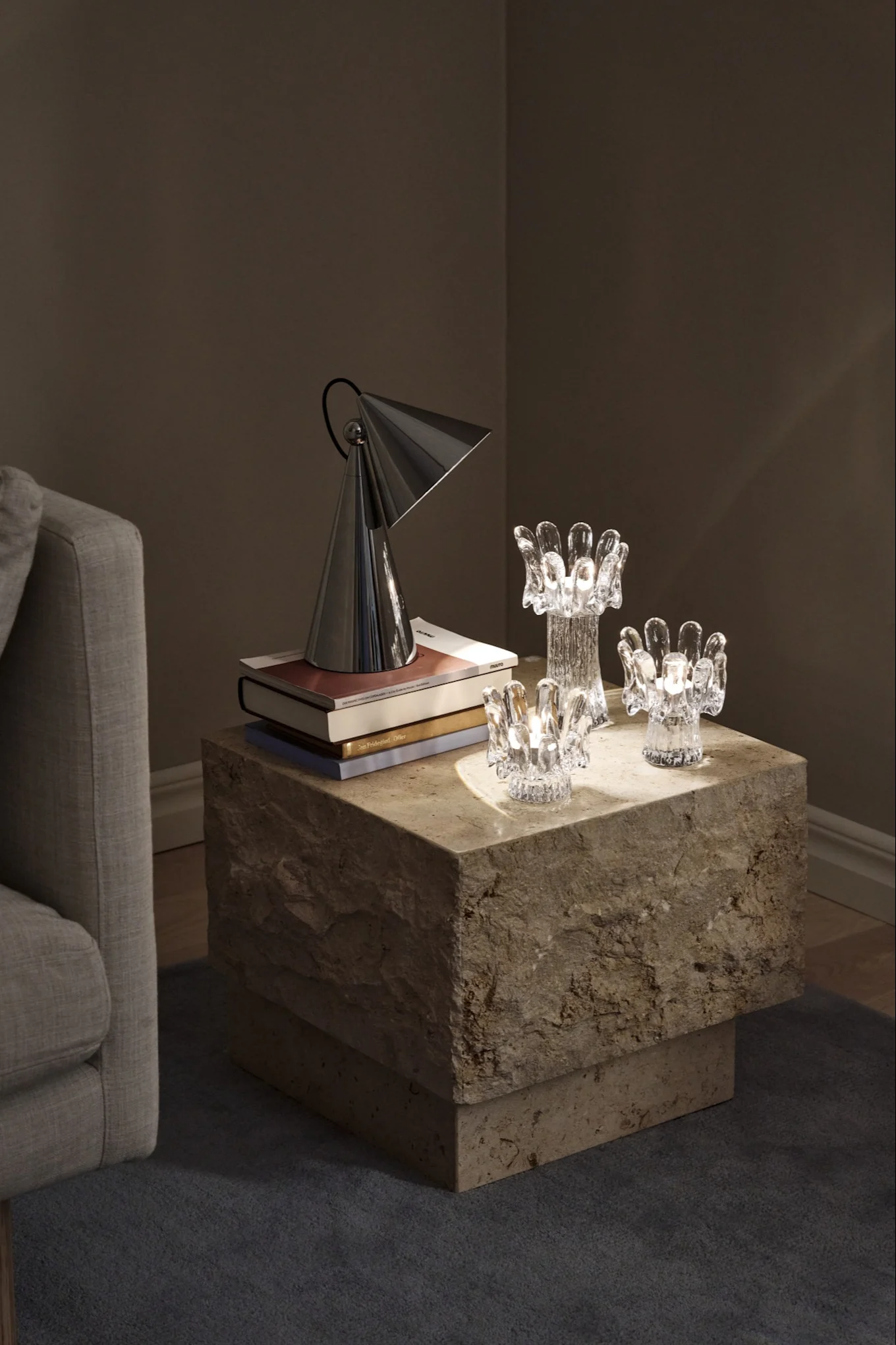 A dark setting illuminated by three glass candle holders shaped like sunflowers, placed on a stone table,  a stylish hint at the interior design trends of 2026.
