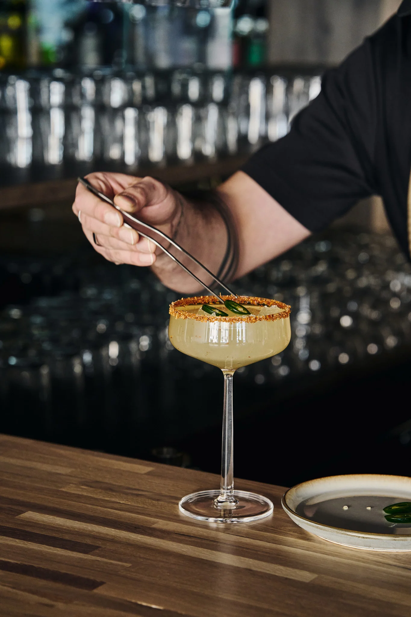 Perfect for mocktails: the Essence cocktail glass by Iittala with drink, decorated rim and garnished with jalapeño slices using tongs.