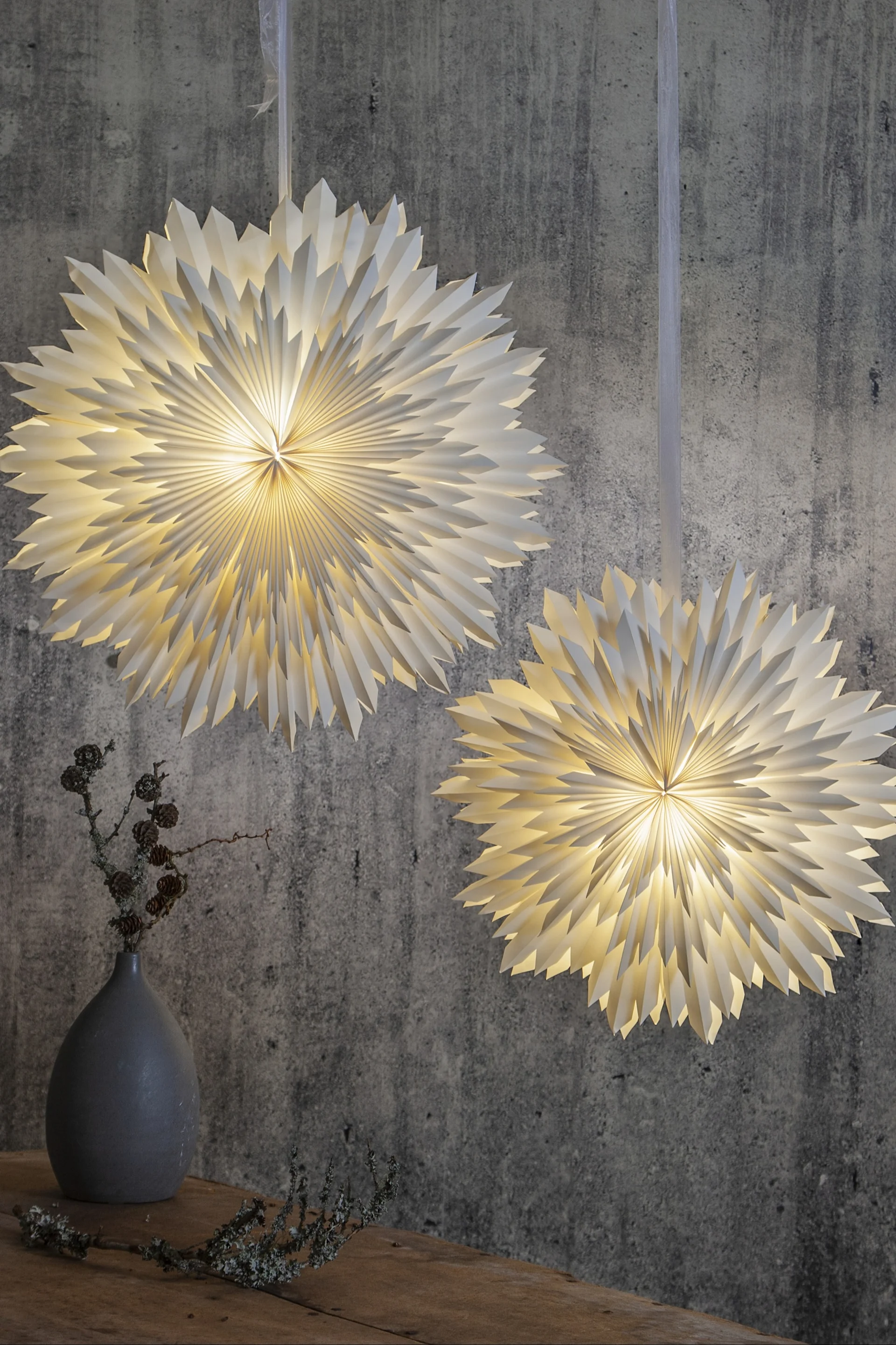 The Christmas star Ice from Star Trading hangs in a pair against a grey wall.