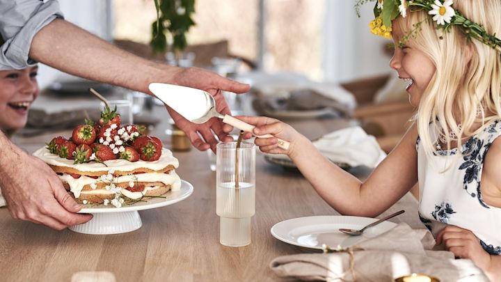 A child is cutting the traditional midsummer strawberry cake. 