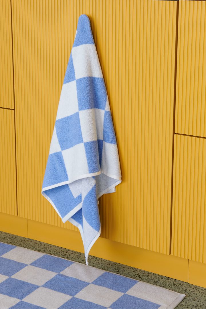 Spring 2024 interior design trends include colourful and patterned textiles, such as the Check bath towel in blue and white from HAY.