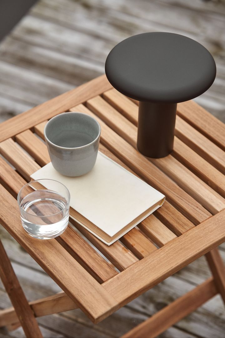 The Takku portable lamp in black from Artemide is a stylish rechargeable lamp that creates a soft and cosy glow on the patio, whether on the small side table or the large dining table.